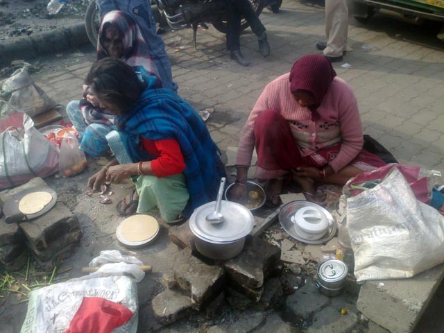 Women cook outside a toilet at the gate of AIIMS.